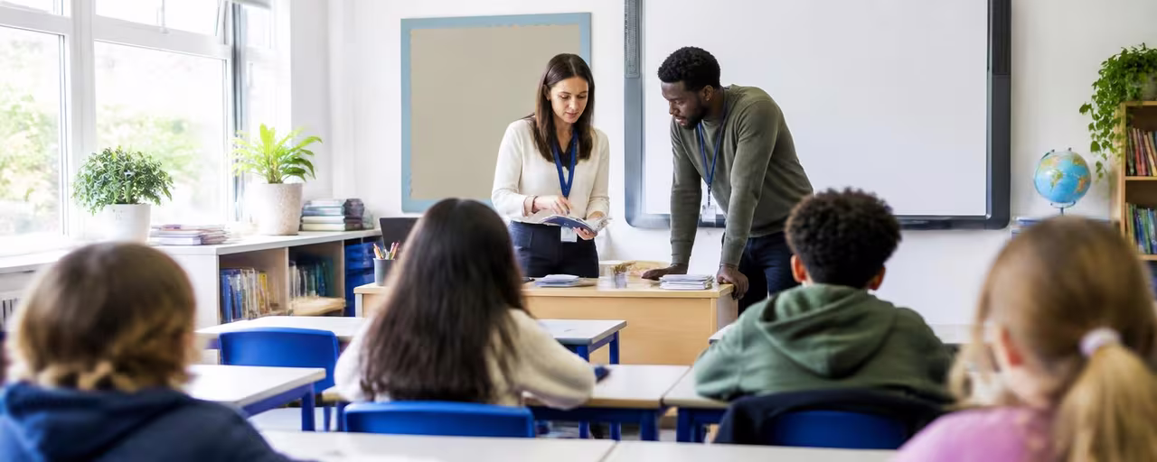 A teaching assistant working with a female teacher in a classroom